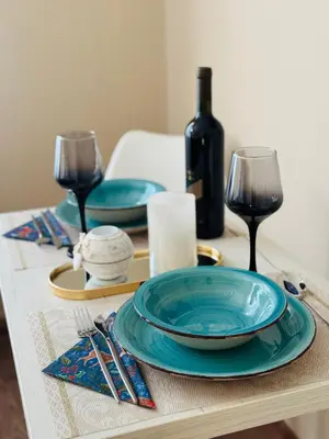 a table with a blue plate and wine glasses at Bella Studio in Podgorica