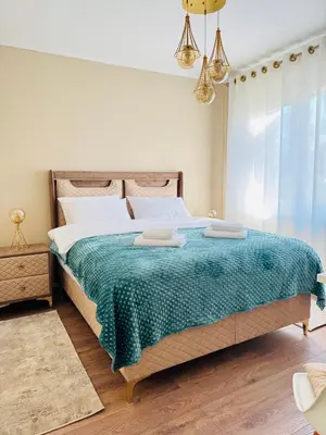 a bedroom with a large bed with a green blanket at Bella Studio in Podgorica