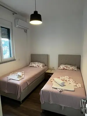 two beds in a small bedroom with a window at Amore in Ulcinj