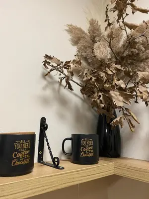 two coffee cups sitting on a shelf with a plant at Lina Apartment in Podgorica
