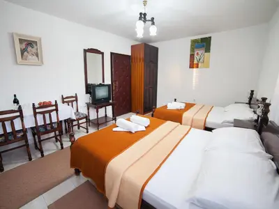 a hotel room with two beds and a television at Guest House 4M in Petrovac na Moru