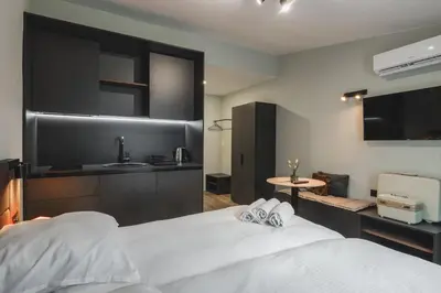 a bedroom with a large white bed and a kitchen at Moon apartment 1 in Podgorica