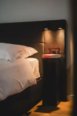 a bedroom with a bed and a night stand with a book at Moon apartment 1 in Podgorica
