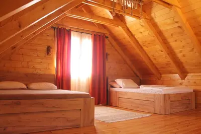 two beds in a log cabin with a window at Cottage retreat- Skadar Lake in Virpazar
