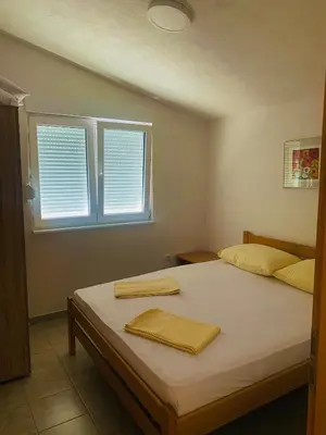 a bedroom with a bed with white sheets and two windows at Spacious Home with Stunning Mountain and Sea Views , Bar, Dobre Vode Montenegro in Bar