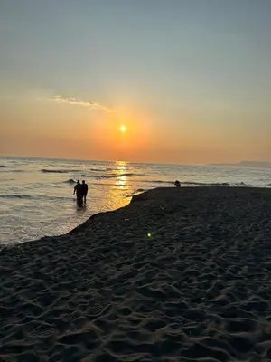 two people standing in the water on the beach at sunset at G4 Apartment in Ulcinj