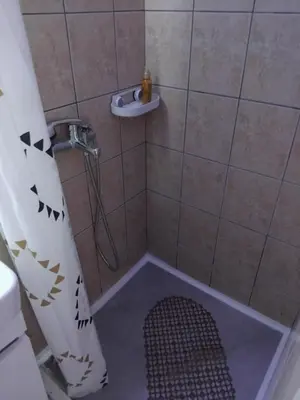 a shower with a shower curtain and a round shower floor at AK apartman in Sutomore