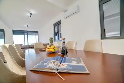 an open book on a wooden table with a dining room at Villa Jelena with private pool - Lapcici in Budva