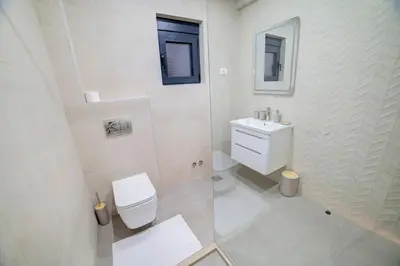a white bathroom with a toilet and a sink at Villa Jelena with private pool - Lapcici in Budva