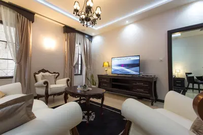 a living room with a television and white furniture at Pearl Apartments in Kotor