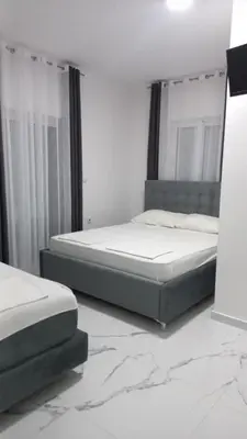 a bedroom with two beds and a marble floor at Apartments Armini in Ulcinj