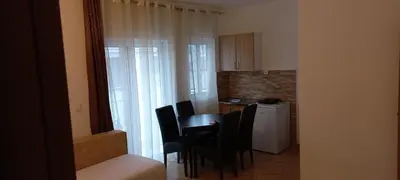 a dining room table with black chairs and a kitchen at Apartments Armini in Ulcinj