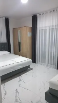a bedroom with a bed with marble floors and curtains at Apartments Armini in Ulcinj