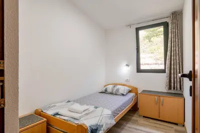 a small bedroom with a bed and a window at Apartmani Sonja i Branko in Sutomore