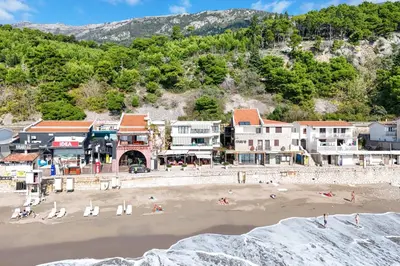 a beach with buildings and people on the sand at Apartmani Sonja i Branko in Sutomore