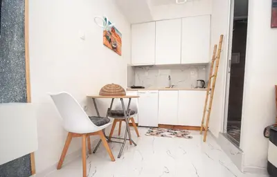 a kitchen with white cabinets and a table and chairs at CENTAR Apartmant in Bar