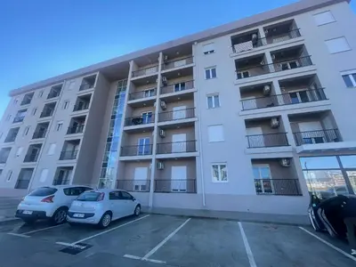 an apartment building with two cars parked in a parking lot at Southern Retreat in Podgorica