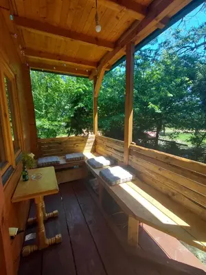 a porch of a wooden cabin with a table and benches at comjun in Ada