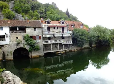 a group of buildings on the side of a river at Rooms Milena in Rijeka Crnojevića