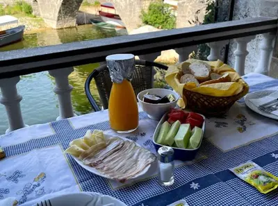 a table with a plate of food and a bottle of juice at Rooms Milena in Rijeka Crnojevića