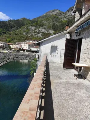 a building with a walkway next to a body of water at Rooms Milena in Rijeka Crnojevića