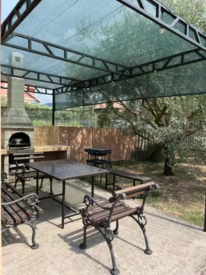 a picnic table and benches under a glass canopy at Apartman MIO in Pržice