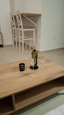 two wine glasses and a bottle on a wooden table at Tims apartment in Mrčevac