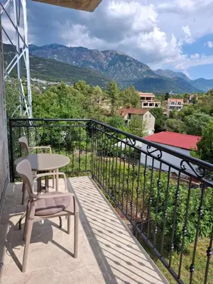 a balcony with a table and chairs and mountains at Tims apartment in Mrčevac