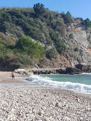 a man walking on a beach next to the ocean at Traumhafte Wohnung mit Meerblick in Sutomore in Sutomore