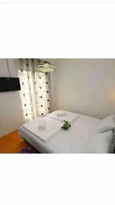 a bedroom with a white bed with a plant on it at Izvor in Budva