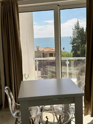 a table and chairs in front of a window with the ocean at Dilan apartments by the sea in Bar