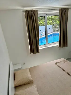 a bedroom with a bed and a window with a swimming pool at Dilan apartments by the sea in Bar