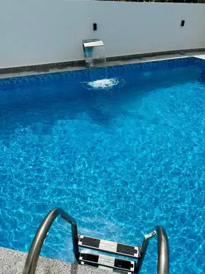 a swimming pool with a chair and a water fountain at Dilan apartments by the sea in Bar
