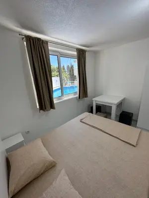 a bedroom with a bed and a desk and a window at Dilan apartments by the sea in Bar
