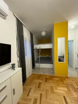 a living room with a tv and a yellow wall at Podgorica apartment - up to 4 persons in Podgorica