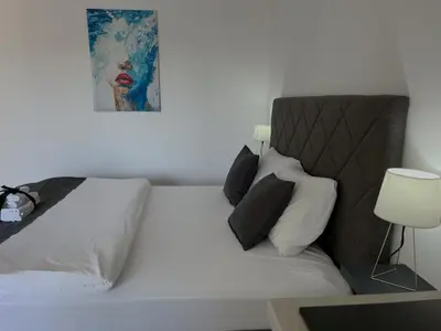 a white bed with black pillows and a picture on the wall at Luxury Lana apartments in Bar