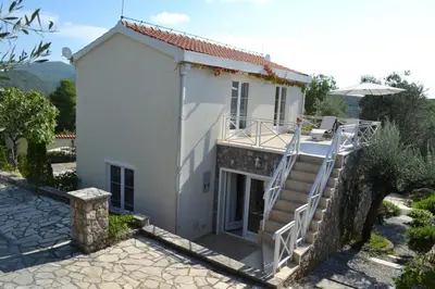 a white house with a staircase in front of it at Suntime Villa 7 in Tivat