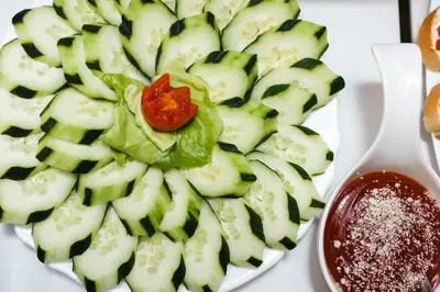 a plate of cucumbers with a tomato on top at Garni Hotel Koral in Budva