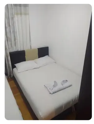 a white bed with two towels on top of it at Stan Budva Rozino in Budva