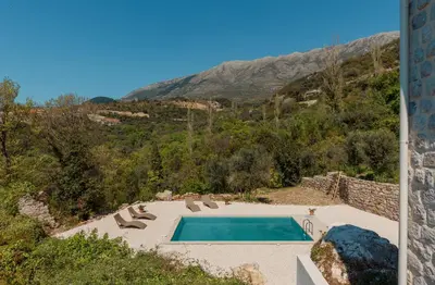 a swimming pool with chairs and a mountain at Villa Magic Stone in Šišići