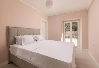 a white bedroom with a large bed with white sheets at Villa Magic Stone in Šišići