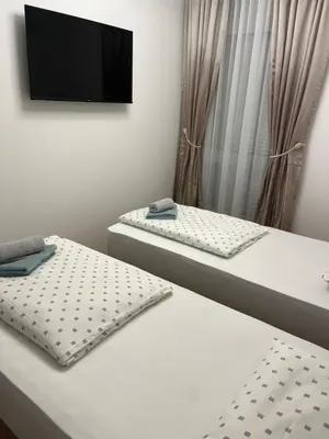 two beds in a room with a tv on the wall at Emel Apartman in Ulcinj