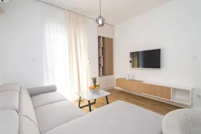 a white living room with a couch and a tv at Montenegrina apartment in Cetinje
