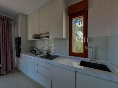 a kitchen with white cabinets and a sink and a window at Olive Residence Rezevici in Budva