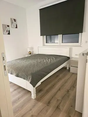 a bedroom with a bed with a green comforter and a window at Porat Apartmani in Ulcinj
