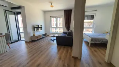 a living room with a couch and a bed and windows at Porat Apartmani in Ulcinj
