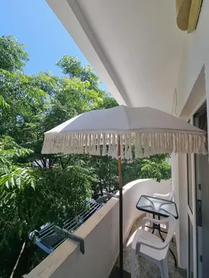 a table and a chair under an umbrella on a balcony at Apartman-Studio Matanović- Save Kovačevića in Sutomore