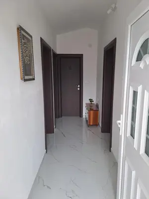 a hallway with a door and a room with white tiles at Plavi Horizont in Utjeha
