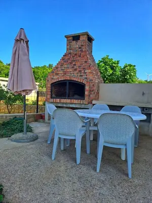 an outdoor table and chairs with a brick fireplace at Plavi Horizont in Utjeha
