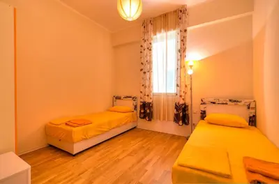 a bedroom with two beds and a window and wooden floors at Sea View Apartments MonteBook in Becici